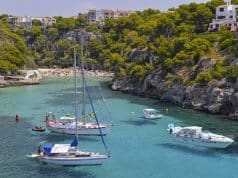 Detalle de Cala Pi, Mallorca con bañistas al fondo y embarcaciones amarradas