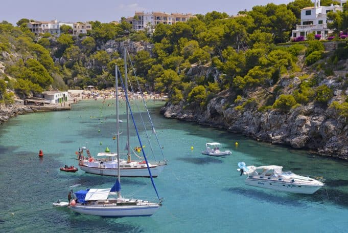 Detalle de Cala Pi, Mallorca con bañistas al fondo y embarcaciones amarradas